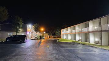 A parking lot with a building that has multiple rooms and a balcony.
