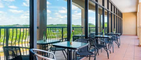 A terrace with outdoor seating, large windows, and a view of the landscape.
