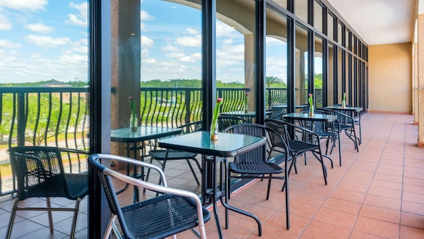 Ein Balkon mit Sitzgelegenheit im Freien, großen Fenstern und Blick auf die Landschaft.