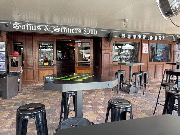 Un pub llamado 'Saints & Sinners Pub' con una zona de bar, taburetes y una mesa con un diseño verde.