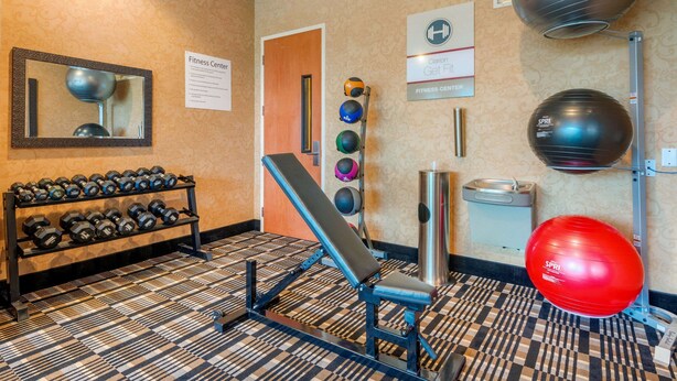 Un gimnasio con equipo de ejercicio, un espejo y un suelo estampado.