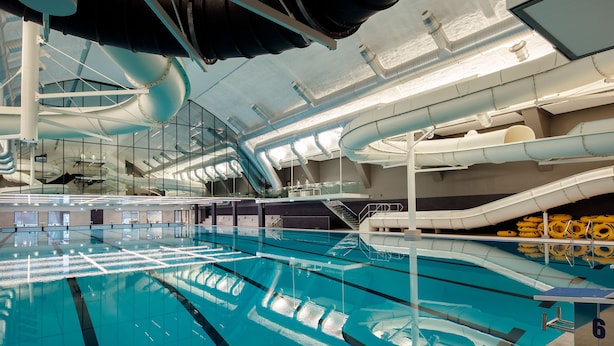 Una piscina cubierta con varias pistas de natación, una plataforma de salto y un tobogán de agua.