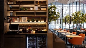Un interior moderno con un mostrador de recepción en tonos oscuros, estanterías con diversos objetos y un techo con diseño.