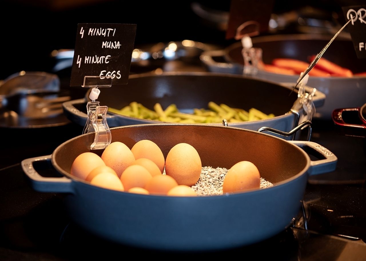 A cooking station with a blue pan filled with eggs and a sign indicating a 4-minute cooking time.