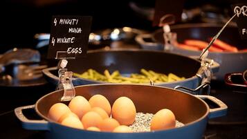 A cooking station with a blue pan filled with eggs and a sign indicating a 4-minute cooking time.