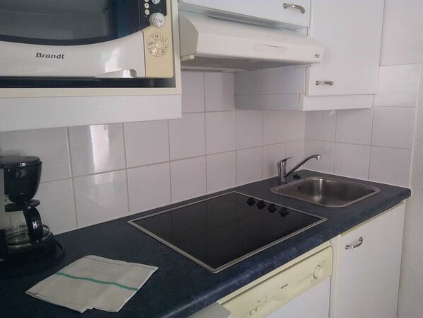 A kitchen with a Brandt microwave, a built-in oven, a sink, and a coffee maker. - Résidence Lagrange Vacances le Hameau de Peemor Pen (Crozon)