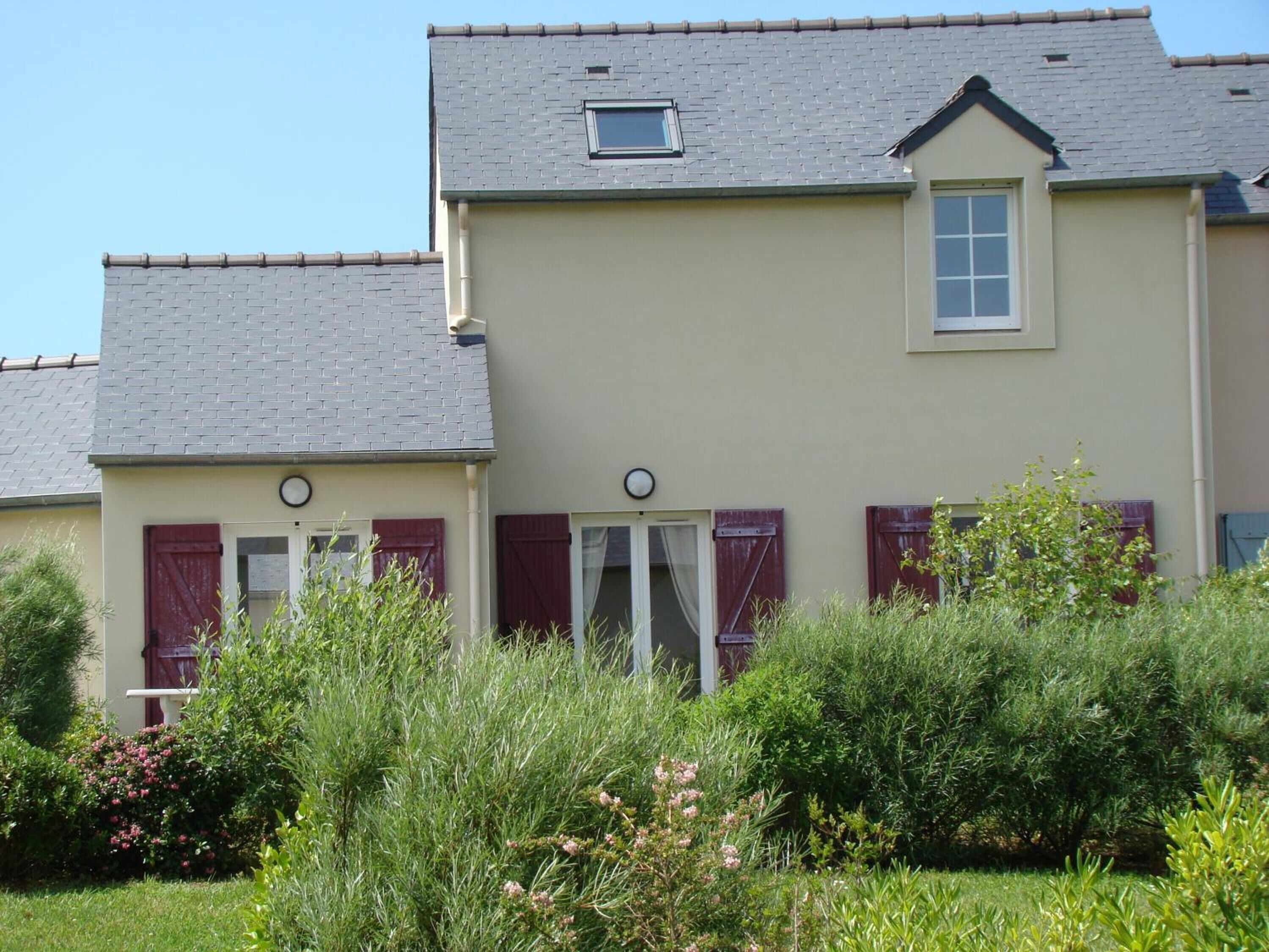 A two-story house with a sloped roof, a small dormer window, and a front door with a white frame.