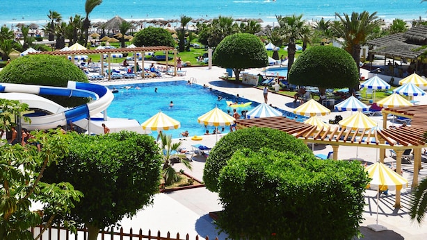 A resort with a swimming pool, beach umbrellas, and palm trees. - Thapsus Beach Resort (Mahdia)
