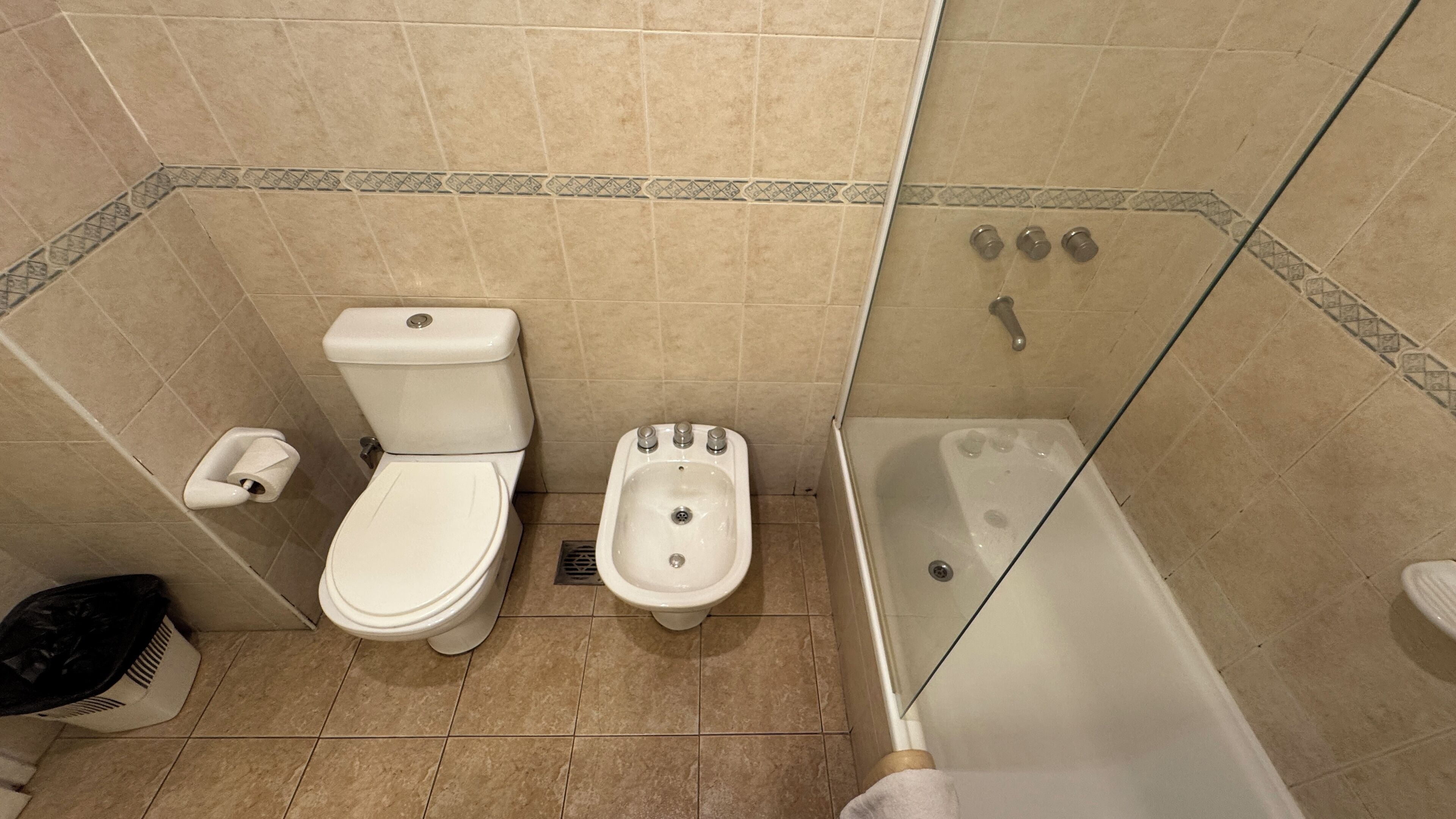 Een badkamer met toilet, bidet en bad.