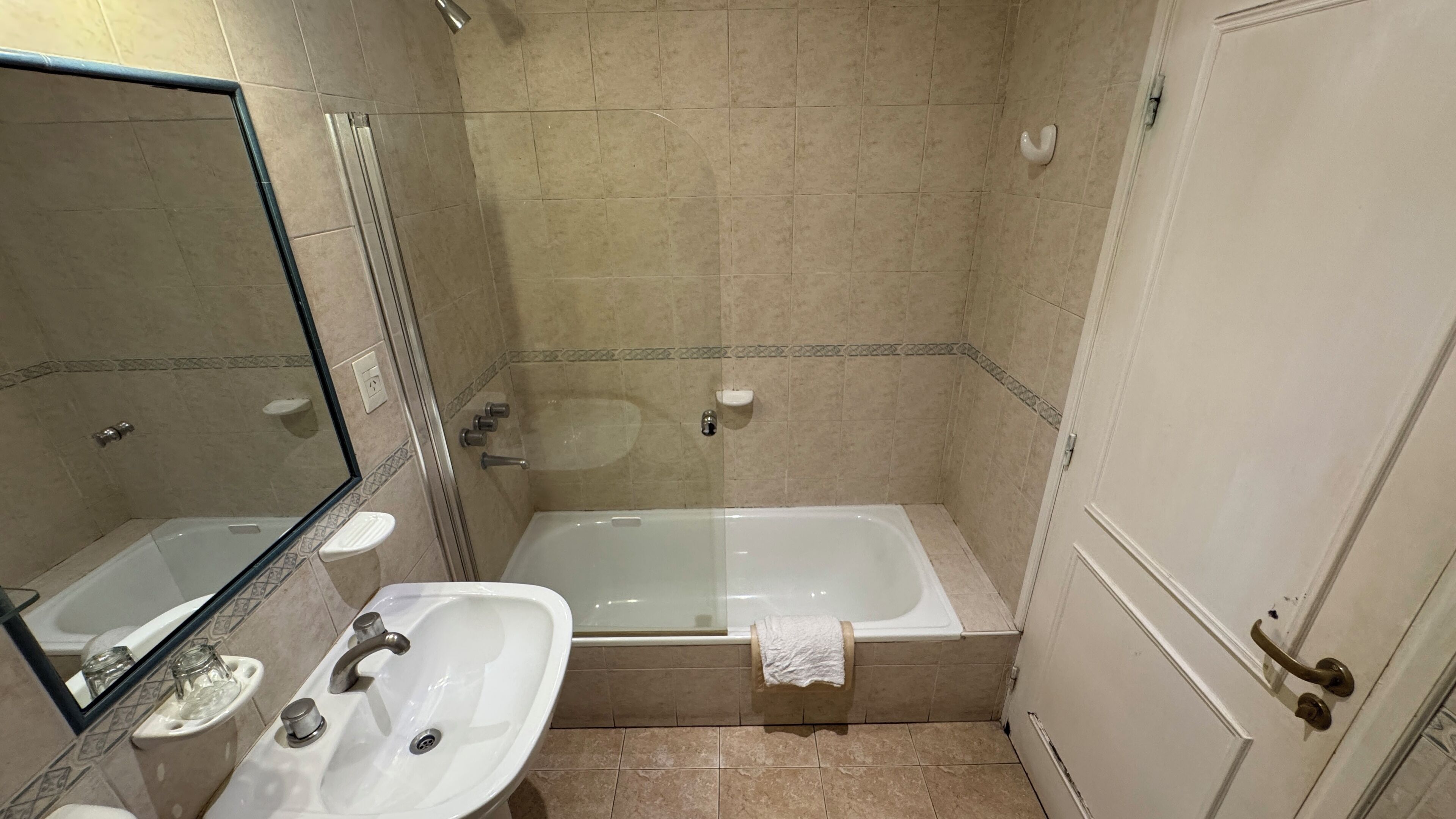 Un baño con bañera, lavamanos, espejo e inodoro.