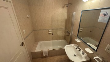 Un baño con bañera, lavabo y espejo.