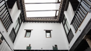 A courtyard with a skylight, white walls, and a chessboard on the floor. - Hotel Rosa D´Oro (Granada)
