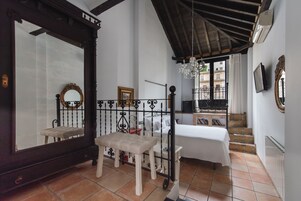 Une chambre à coucher comprenant un lit, un banc, un grand miroir et un escalier menant à un espace extérieur.