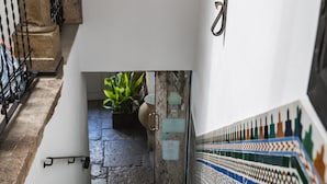 A staircase with a patterned wall, a lamp, and a plant at the bottom. - Hotel Rosa D´Oro (Granada)
