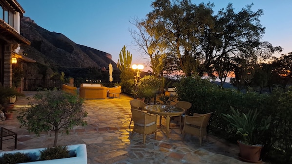 A patio area with stone flooring, wicker furniture, and potted plants. - Hotel Los Jarales (Istan)