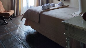 A hotel room with a bed, a chair, a round window, and curtains. - Hotel Los Jarales (Istan)