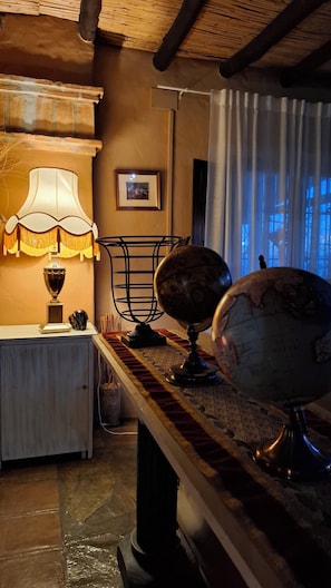 A room with a wooden table, a globe, a lamp, and a framed picture on the wall. - Hotel Los Jarales (Istan)