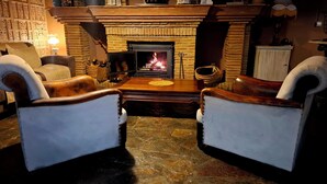 A cozy room with a fireplace, leather armchairs, and a wooden coffee table. - Hotel Los Jarales (Istan)
