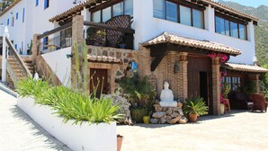 A two-story building with a balcony, a statue, and potted plants. - Hotel Los Jarales (Istan)