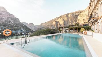 Una piscina al aire libre, sombrillas, tumbonas