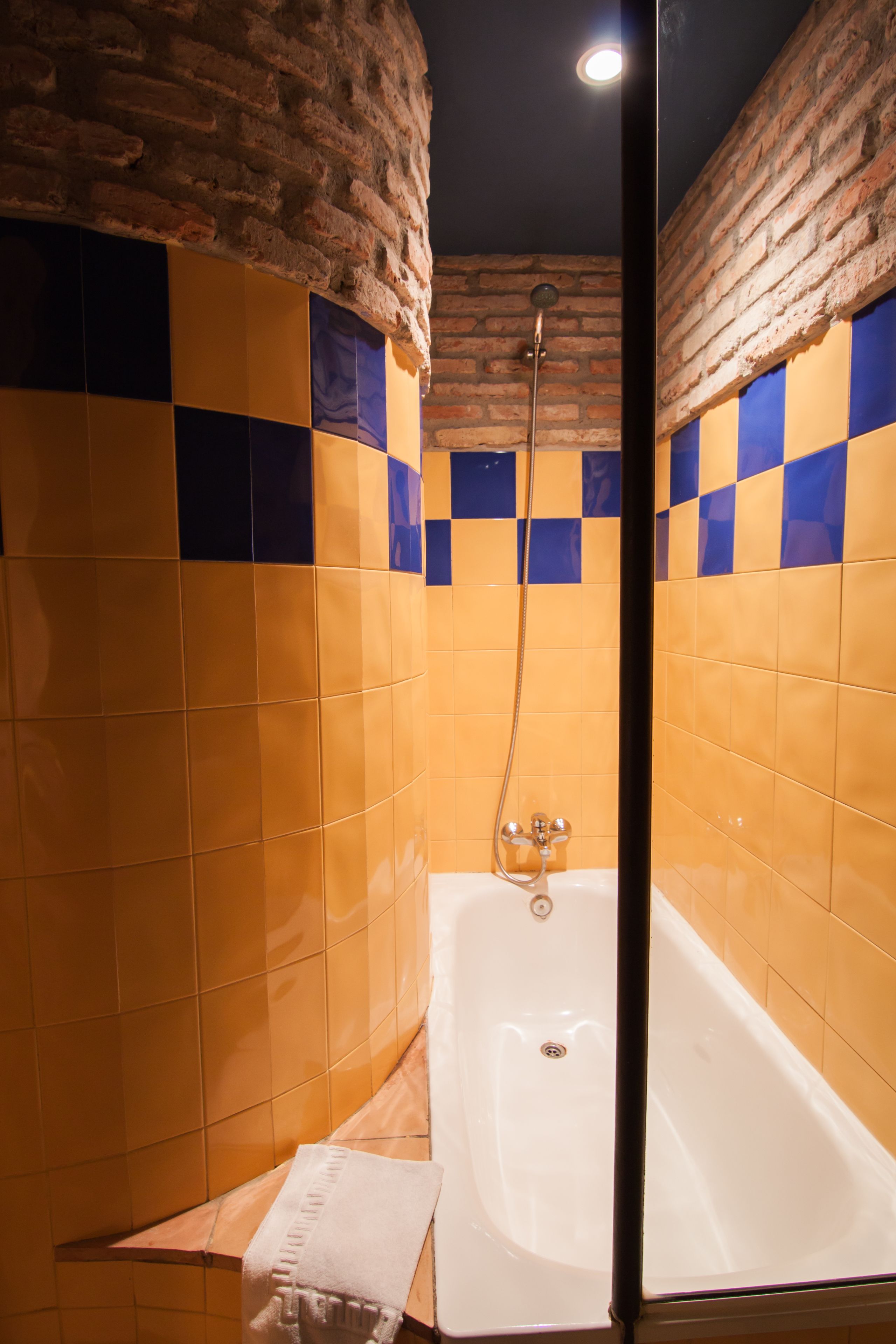 A bathroom with a bathtub, a shower, and a tiled wall with a brick pattern.