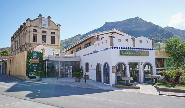 A hotel with a traditional architectural style, featuring a prominent entrance with arched windows and a sign indicating it is 'La Garganta Restaurante Hotel'.