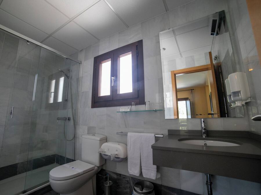 Un baño moderno con ducha de vidrio, inodoro, lavamanos y espejo.