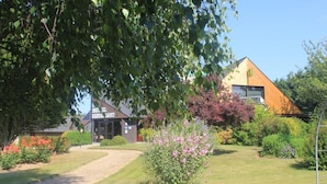 A building with a sign reading "HOTEL RESTAURANT" and a well-maintained garden with a pathway leading to the entrance. - LOGIS Les Dineux Village (Tremeur)