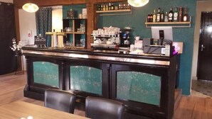 A bar area with a counter, chairs, and shelves with bottles. - LOGIS Les Dineux Village (Tremeur)