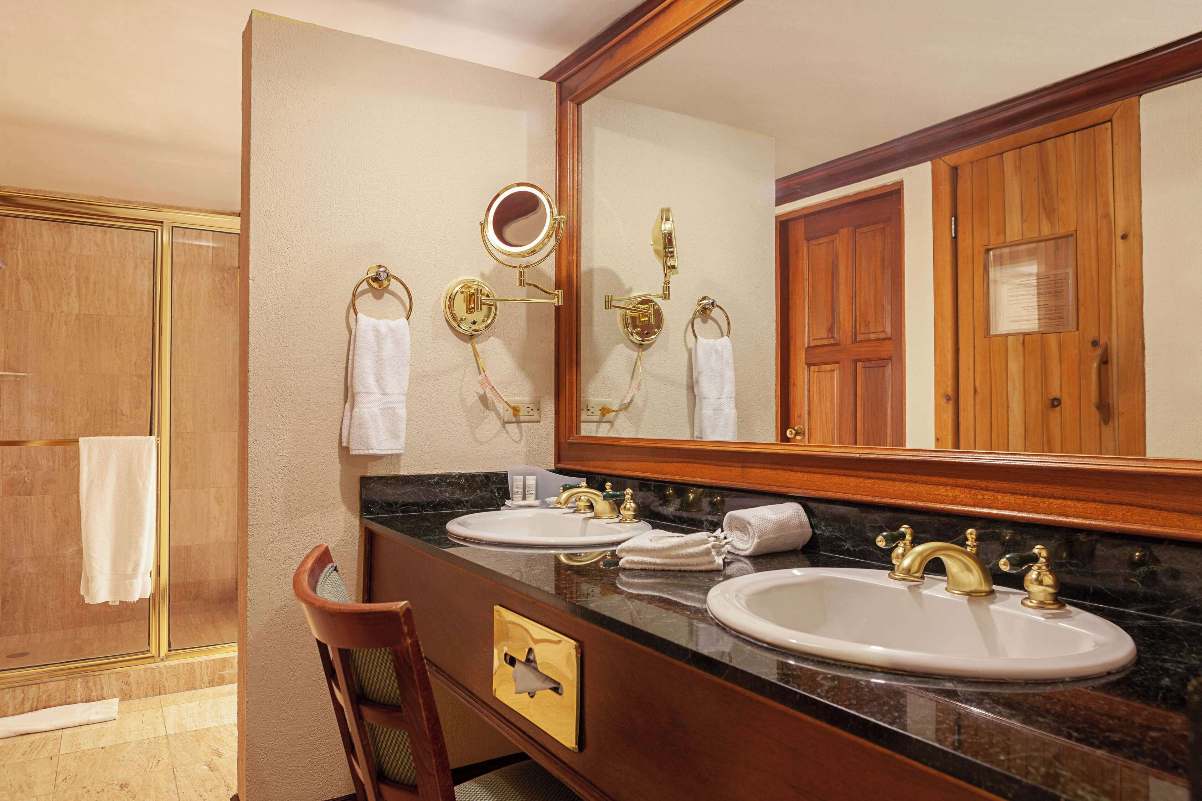 A bathroom with two sinks, a large mirror, and a shower.