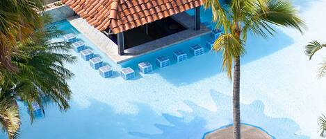 Un resort con zona de piscina, área de descanso cubierta y palmeras.