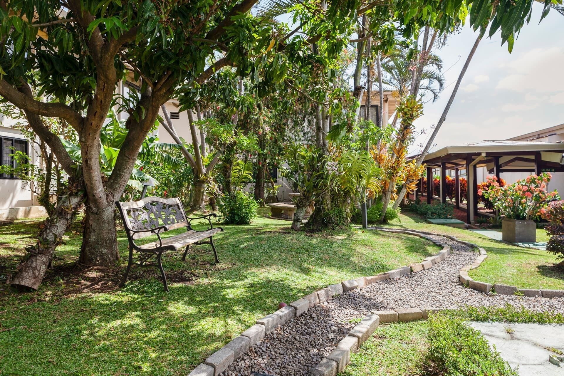 A garden with a bench, a pathway, and a covered area with flowers.