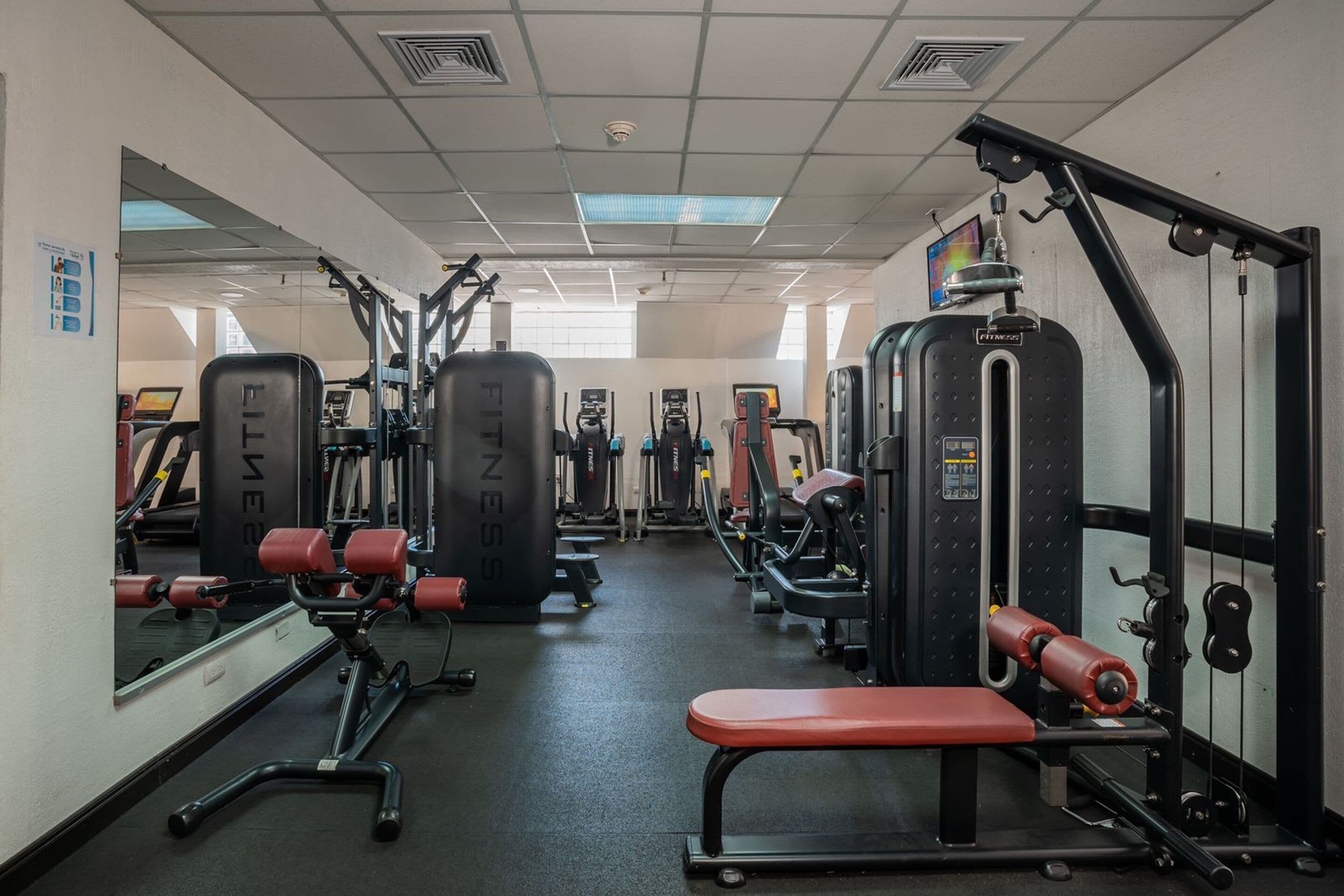 A gym with various exercise equipment, including weight machines and benches.