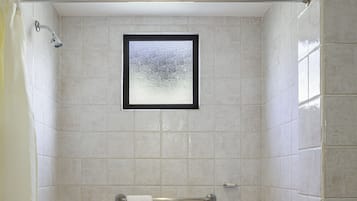 A walk-in shower with a framed picture on the wall, a towel rack, and a shower curtain.