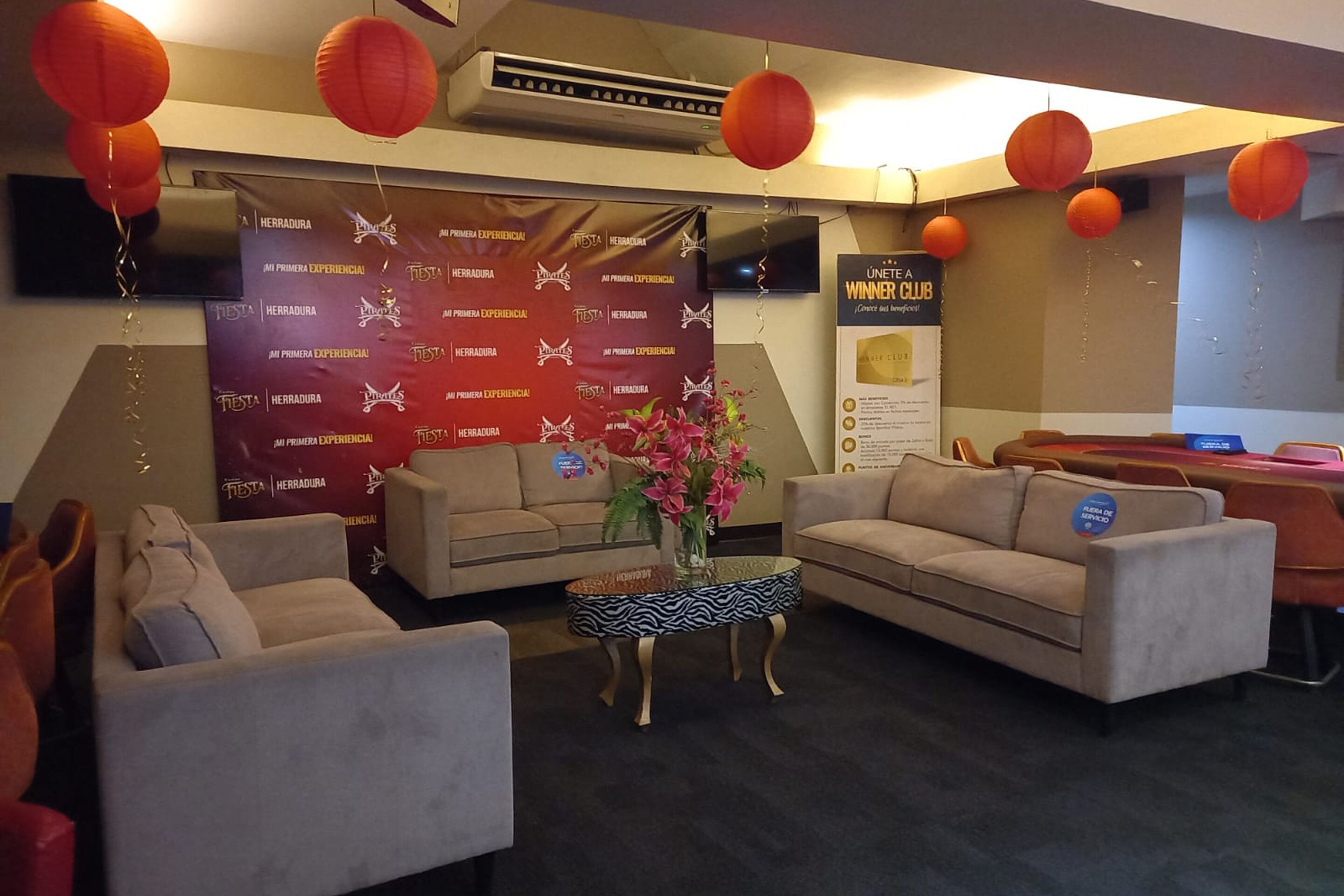 A hotel lobby with sofas, a coffee table, and a banner with event information.