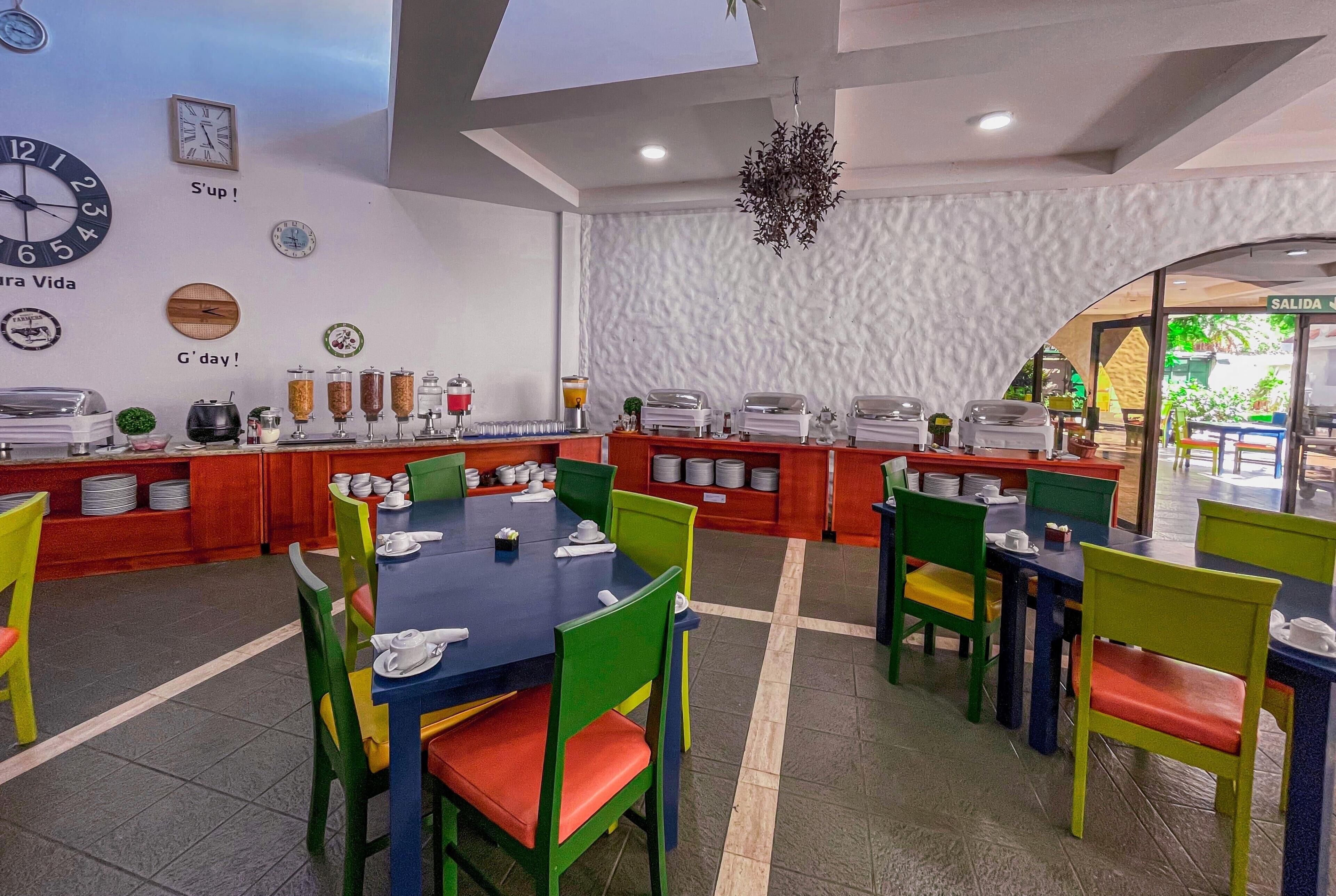 A restaurant with multiple tables and chairs, a clock, and a wall clock.