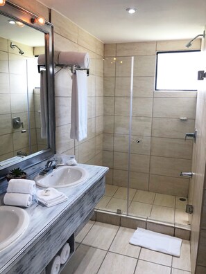 A modern bathroom with two sinks, a large mirror, and a glass-enclosed shower. - Wyndham San Jose Herradura Hotel & Convention Center (La Asunción)