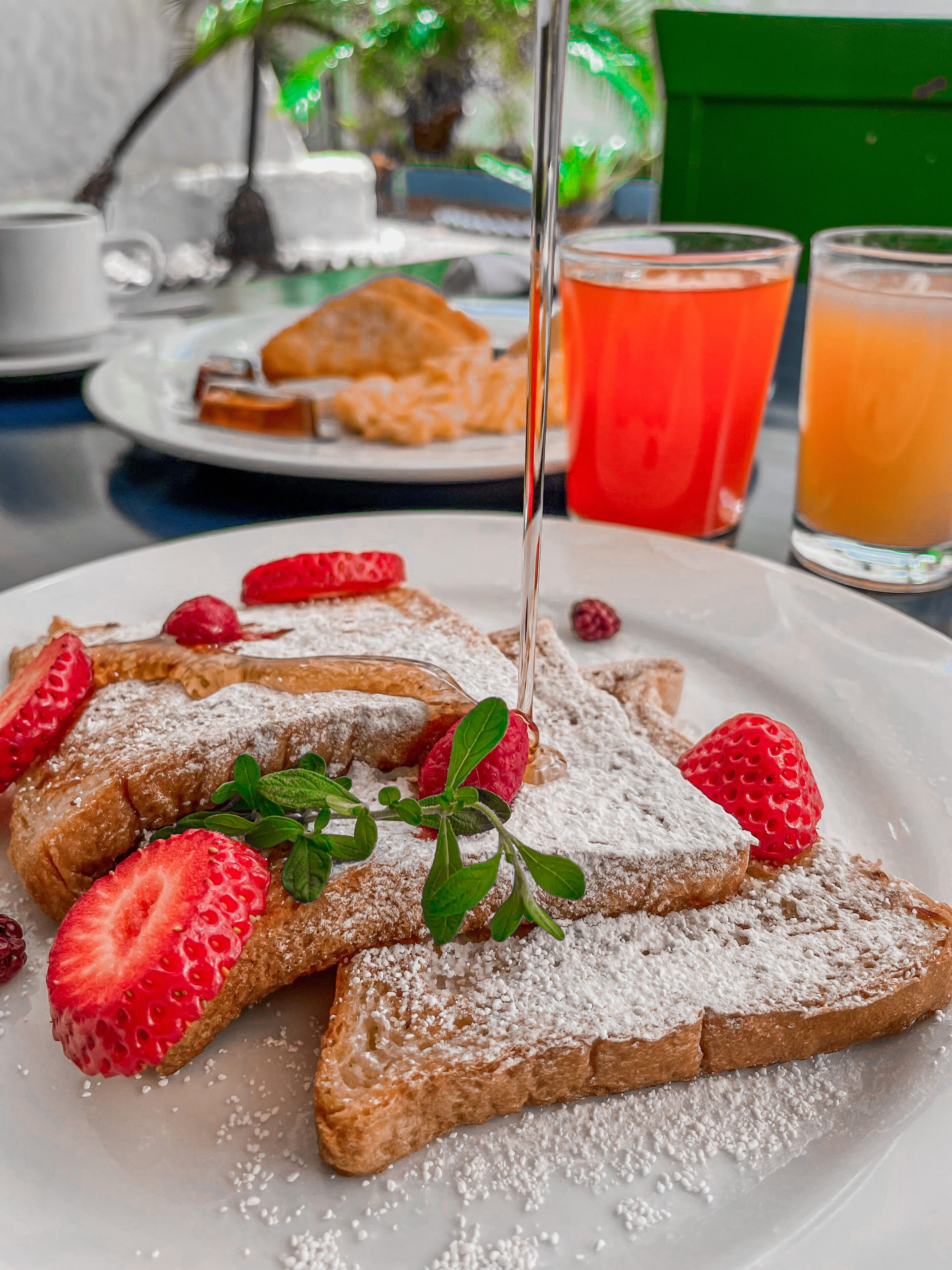 A breakfast setting with French toast, strawberries, and powdered sugar on a plate.