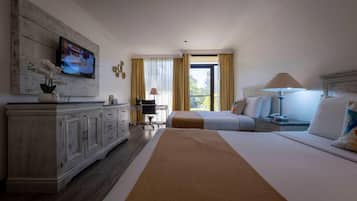 A hotel room with a large bed, a desk, a television mounted on a wooden panel, and a window with curtains.