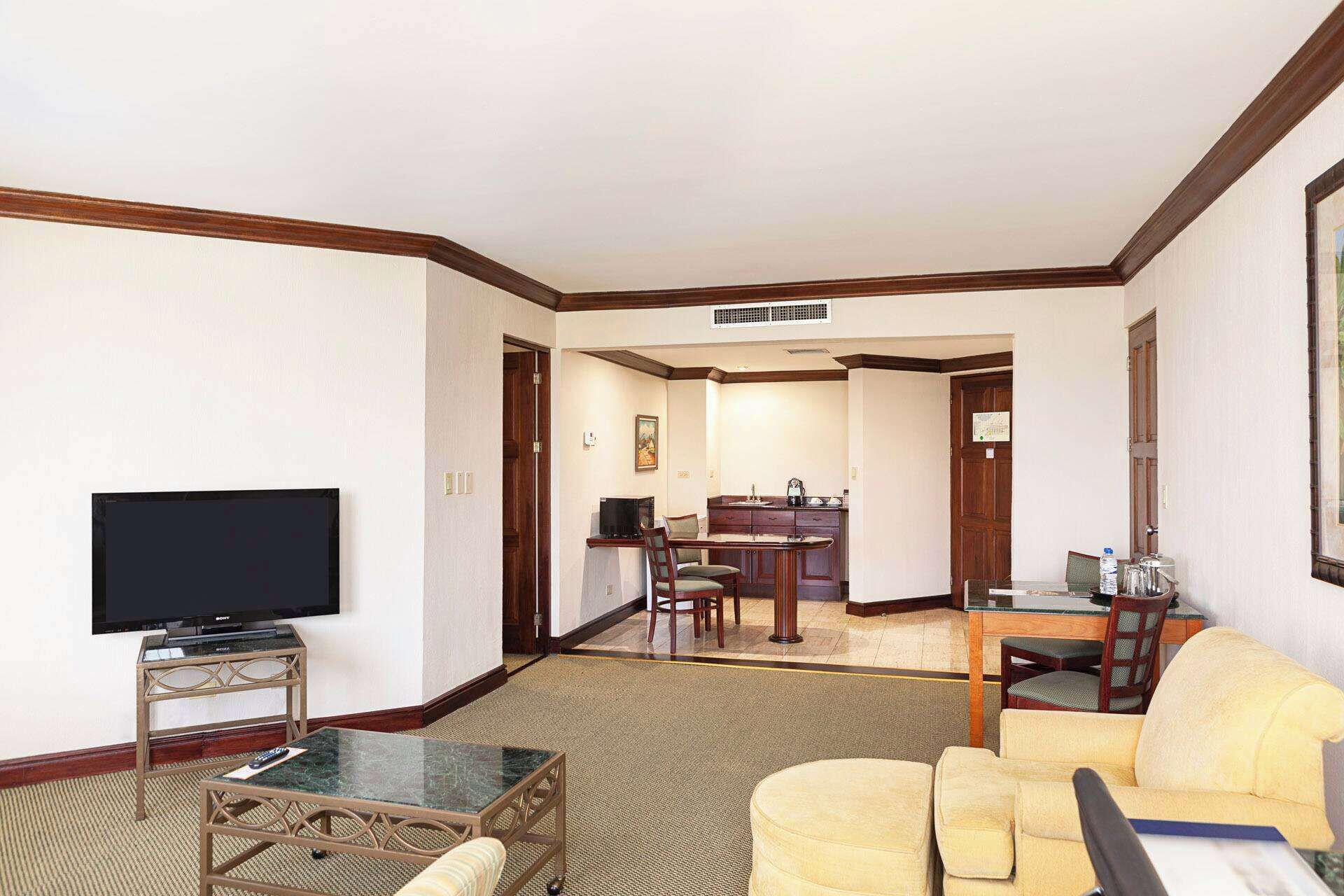 A hotel room with a living area, a dining area, and a kitchenette.