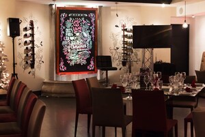 A dining area with a long table set for multiple guests, a large framed poster on the wall, and a television mounted on the wall.