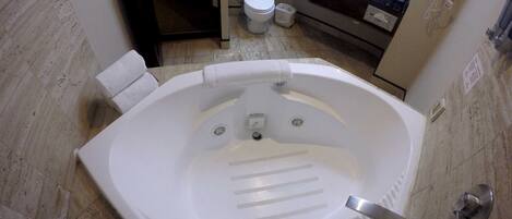 Un baño con una bañera grande, un inodoro y un lavabo.