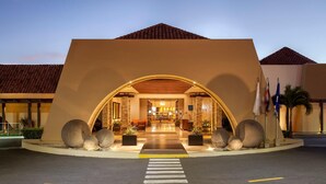 Entrada de un hotel con un amplio arco, una recepción y un paso de peatones que lleva a la entrada.