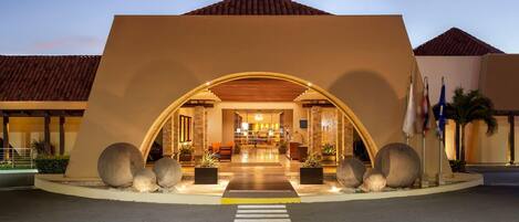 A hotel entrance with a large archway, a reception desk, and a crosswalk leading to the entrance.