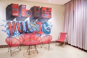 Une pièce avec un mur couvert de graffitis, des chaises rouges et une table rouge.