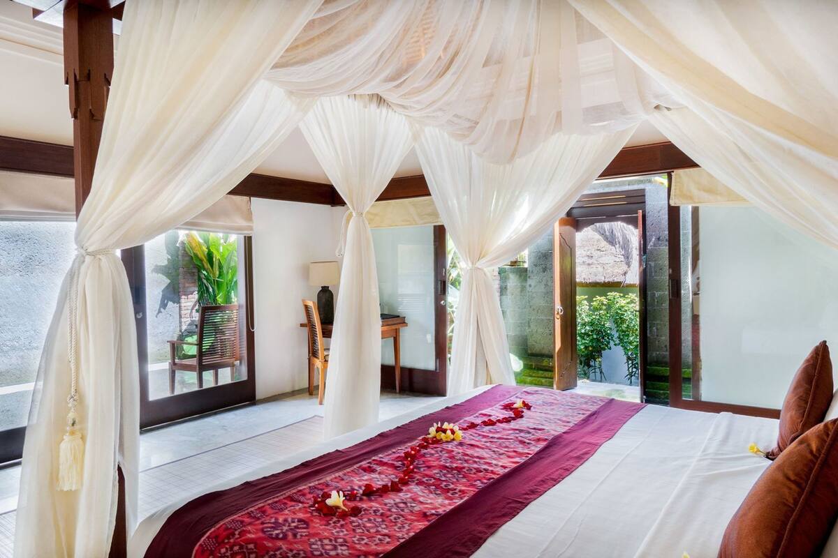 Une chambre à coucher avec un lit à baldaquin, une vue sur le jardin et un balcon.