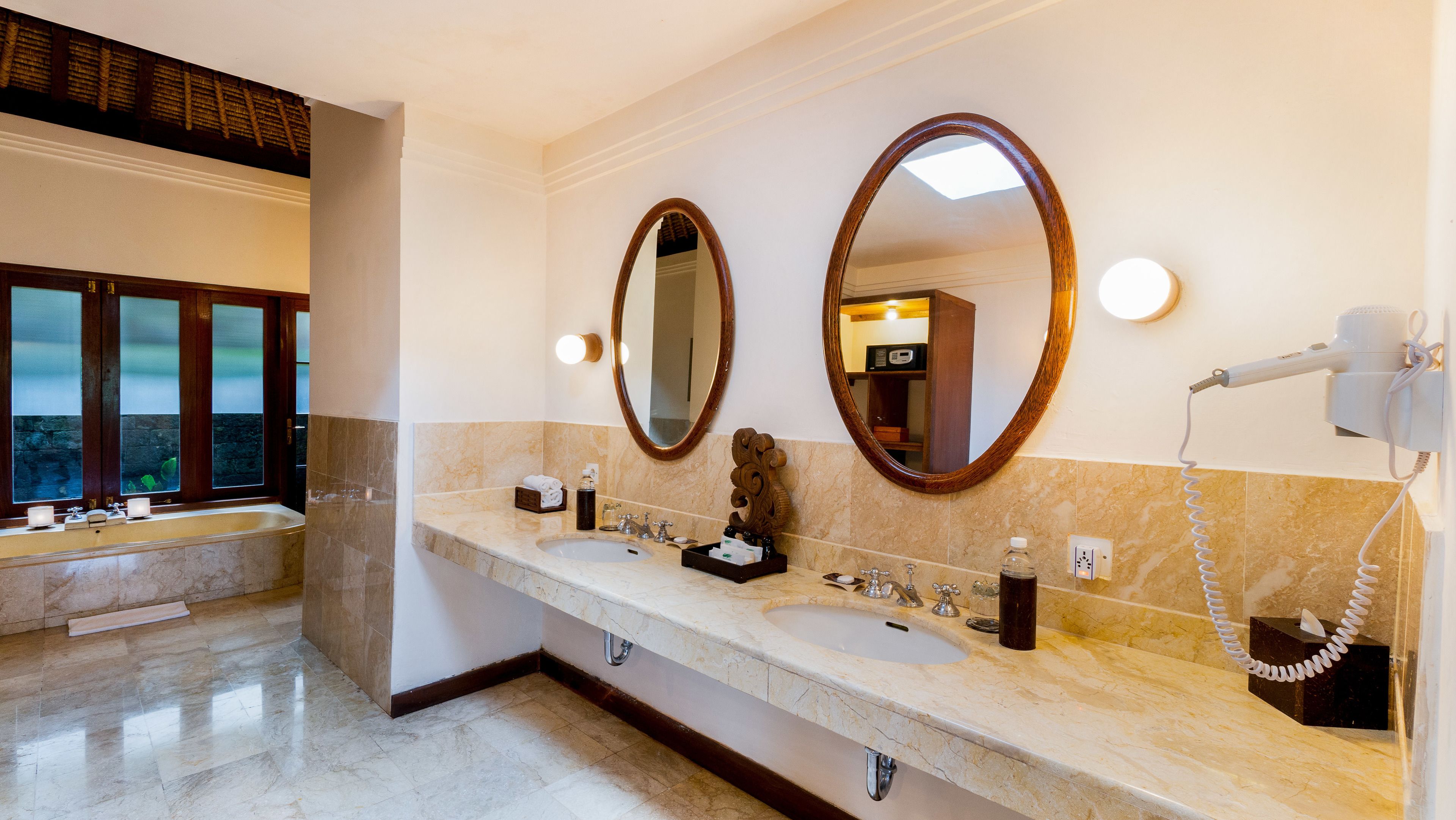 Une salle de bain avec deux lavabos, un grand miroir et un sèche-cheveux fixé au mur.