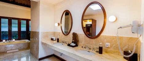 Une salle de bain avec deux lavabos, un grand miroir et un sèche-cheveux fixé au mur.