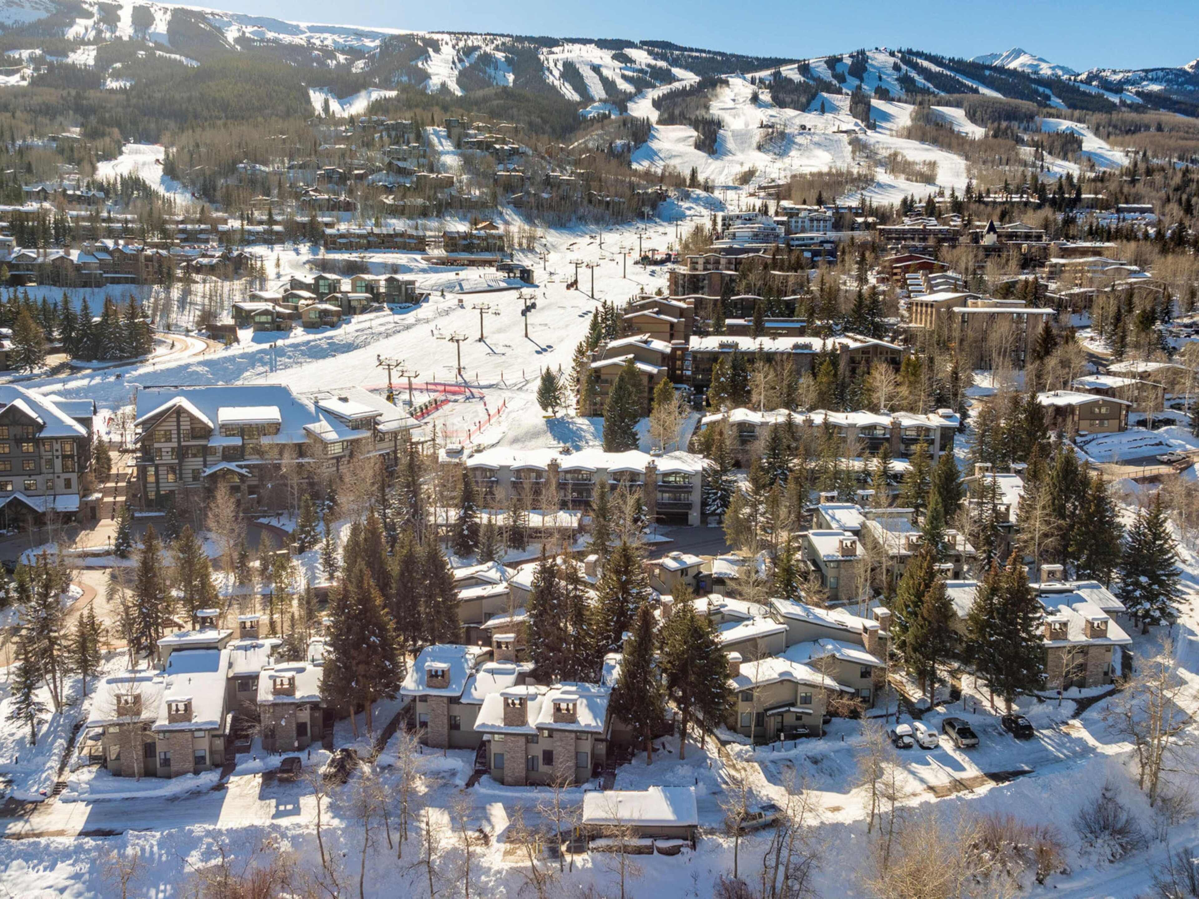 Ein schneebedecktes Resort mit mehreren Gebäuden, Skipisten und einer Seilbahn.