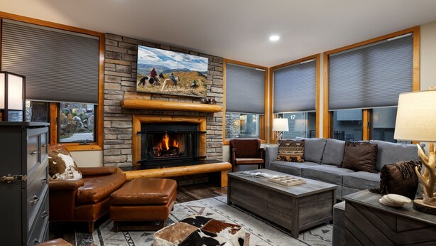 A modern living room with a fireplace, leather furniture, and large windows with blinds. - Tamarack Townhomes - CoralTree Residence Collection (Snowmass Village)